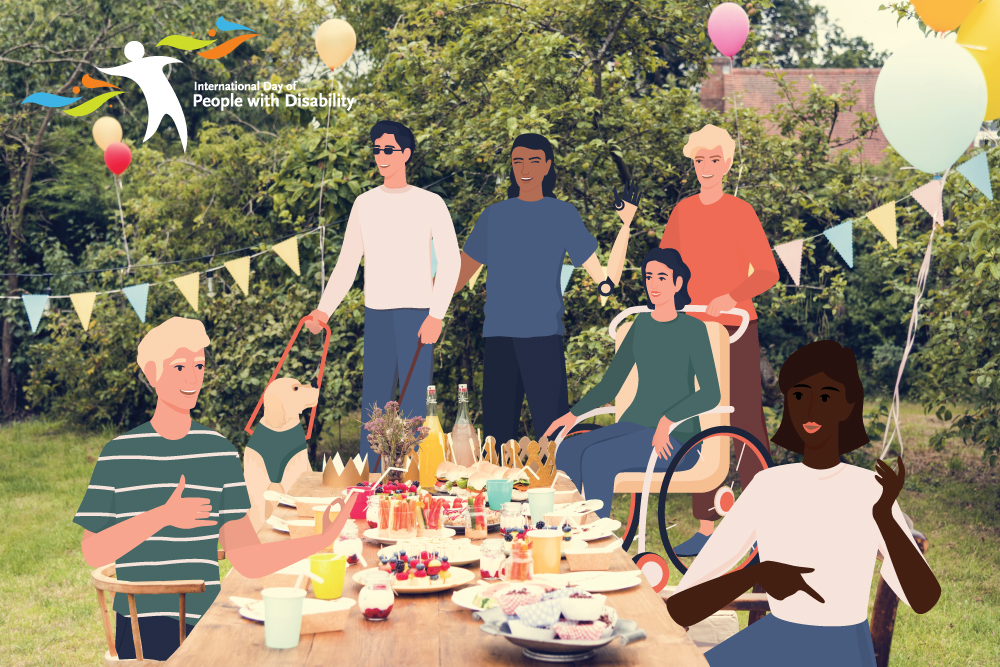 People celebrating at a picnic table in a backyard. There is food on the table and people are chatting and laughing. One person has a guide dog and one is in a wheelchair. Two people appear to be using sign language to converse.